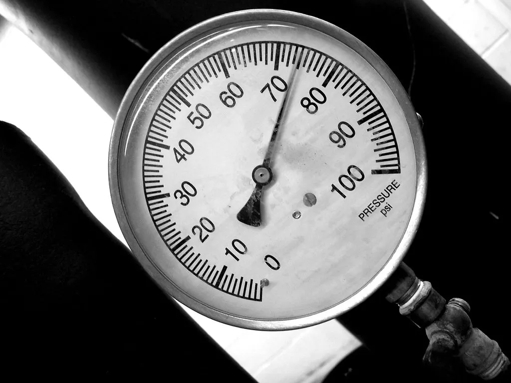 Analog air pressure gauge reading in PSI on an industrial air line