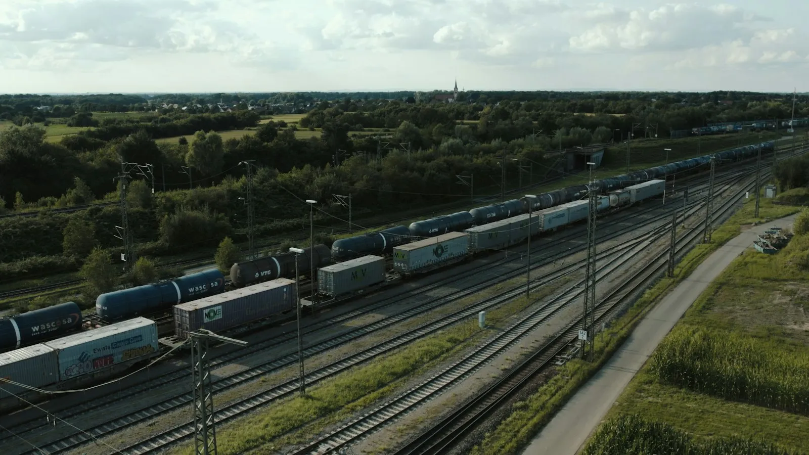 A train traveling down train tracks next to a lush green field